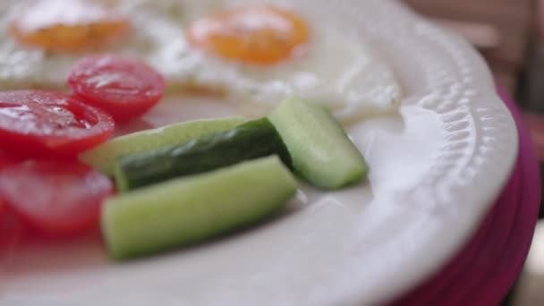 Friska frukosttallrik med stekta ägg, tomater, gurka och avokado på bordet — Stockvideo