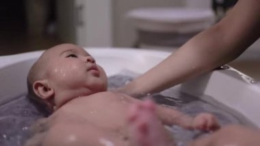 Asyalı bebek yıkanıyor ve eğleniyor.