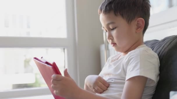 Asyalı çocuk tableti tutuyor ve ekrana dokunuyor. — Stok video