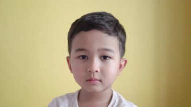 Tatlı çocuk kameraya bakıyor ve arka planda çok üzgün görünüyor.