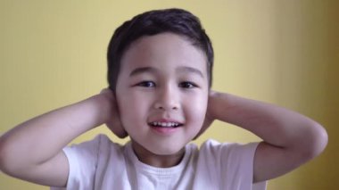 Sevimli çocuk kulaklarını renkli palmiyelerle kapatıyor.