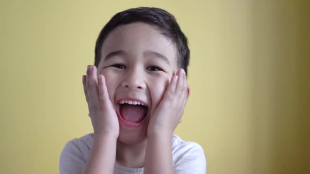 Niño emocional sorprendente y sonriente y sobre fondo de color — Vídeos de Stock