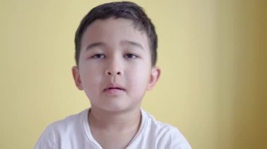 Sevimli çocuk gülümsüyor ve yüzünü renk arka planında örtüyor.. 