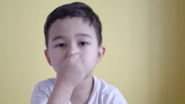 Tatlı çocuk, burnunu renkli arka planda kapatıyor.. 