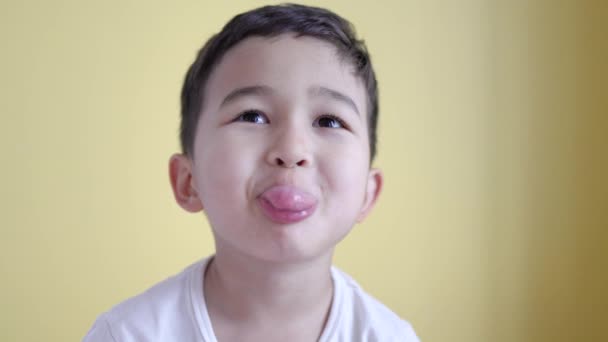 Cute boy pokazać swój język na tle koloru. — Wideo stockowe
