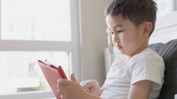 Asiático chico sosteniendo tableta y tocando la pantalla —  Fotos de Stock