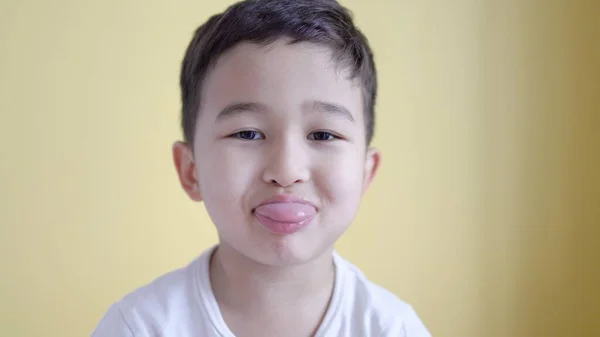Netter Junge zeigt seine Zunge auf farbigem Hintergrund. — Stockfoto
