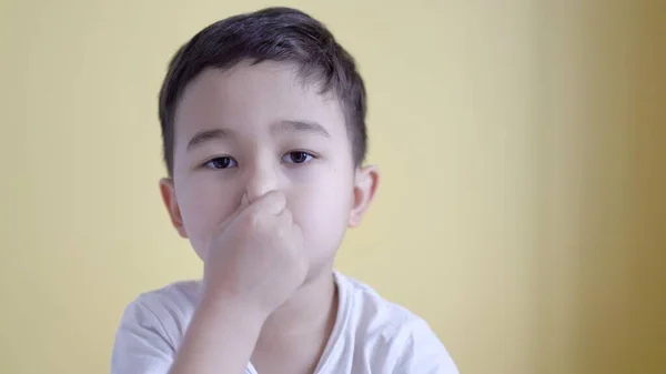 Cute boy close his nose on colour background. — Stock Photo, Image