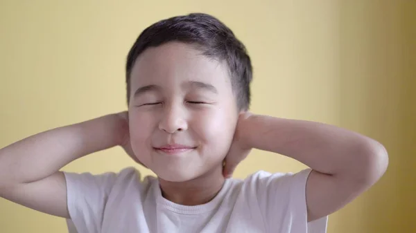 Netter Junge bedeckt Ohren mit Handflächen auf farbigem Hintergrund — Stockfoto