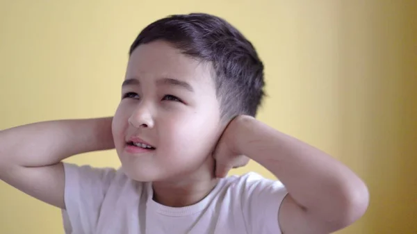 Bonito menino cobre orelhas com palmas na cor de fundo — Fotografia de Stock