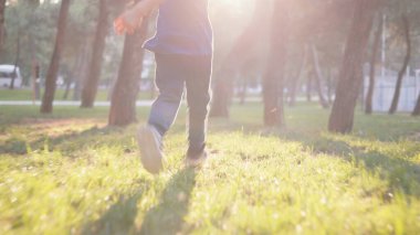 Gün batımına karşı ağaçlarla parkta koşan yüzü olmayan bir çocuk. Yüksek kalite 4k görüntü