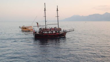 Turist gemileri gün batımında denize açılır ve arka planda dağlar vardır. Yüksek kalite 4k görüntü