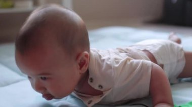Bebek karnının üstüne yatar ve başını tutmaya çalışır. Yüksek kalite 4k görüntü