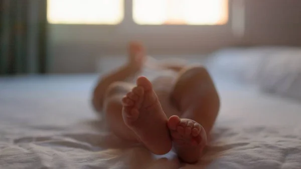 Μωρό Άσπρα Ξαπλώνει Στο Κρεβάτι Και Κουνάει Πόδια Του Υψηλής — Φωτογραφία Αρχείου