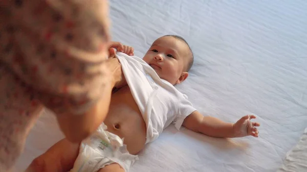 Mother changes clothes of the baby lying on the bed. High quality 4k footage