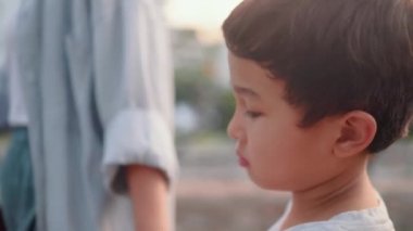 Üzgün çocuğun yakın görüntüsü annelerin elini tutuyor ve onun yanında yürüyor. Yüksek kalite 4k görüntü