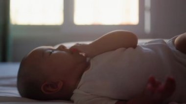 Cute asian baby on bed put hands into mouth. High quality 4k footage