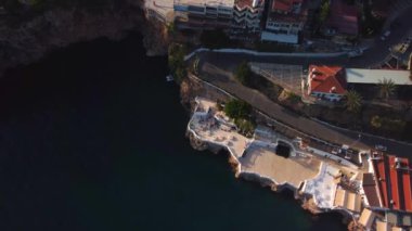 Gün batımında deniz kenarında kıvrımlı yolu olan adanın en üst hava manzarası. Yüksek kalite 4k görüntü