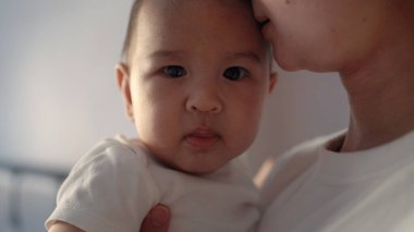 Anne bebeğini kucağında tutuyor. Kameraya bakan şirin bebeğin yakın görüntüsü. Yüksek kalite 4k görüntü