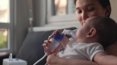 Mother is holding an inhaler in front of the babys face. High quality 4k footage