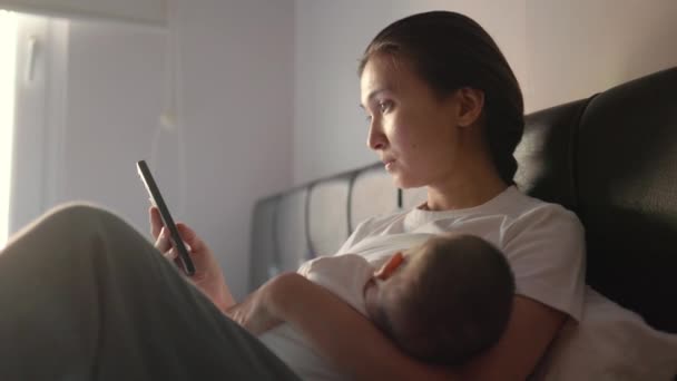 Tired Young Mother Breastfeeding Her Baby Shopping Mobile Phone High — Stockvideo