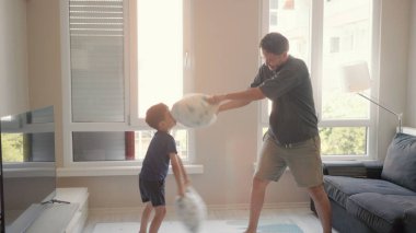 Young Father and little son enjoy pillow fighting sit on sofa at home. High quality 4k footage