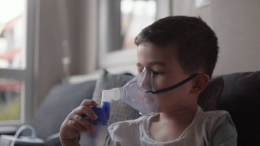 Astım spreyinden buhar soluyan bir çocuk. Akciğer hastalıklarının tedavisi. Yüksek kalite 4k görüntü
