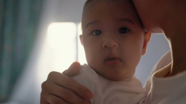 Anne bebeğini kucağında tutuyor. Kameraya bakan şirin bebeğin yakın görüntüsü. Yüksek kalite 4k görüntü