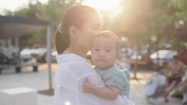 Happy mom holding cute small baby. Happy family in park. High quality 4k footage
