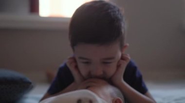 Adorable preschooler plays with his baby brother at floor. High quality 4k footage