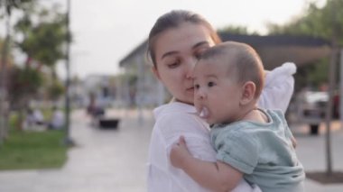  Cute baby spitting milk up while mom holds him in her arms. High quality 4k footage