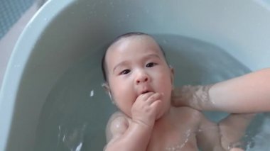 Top view of Cute baby having bath. Mother holds and bathes baby. High quality 4k footage