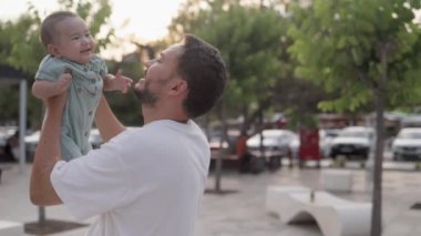Happy father is holding cute baby and kisses while he is laughing. High quality 4k footage