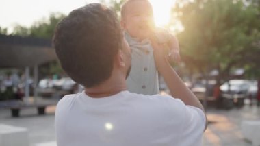 Happy father is holding cute baby and kisses while he is laughing. High quality 4k footage