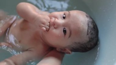 Top view of Cute baby having bath. Mother holds and bathes baby. High quality 4k footage