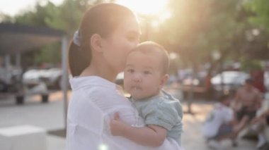  Happy mom holding cute small baby. Happy family in park. High quality 4k footage