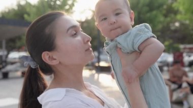 Happy mom holding baby in front of the sun. Happy family in park. High quality 4k footage