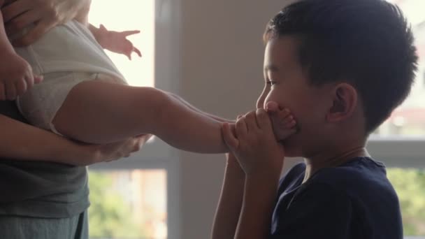 Cute Preschooler Plays His Baby Brothers Legs Kiss Them High — Stock video