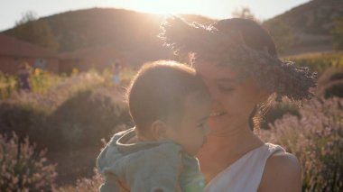 Beautiful woman with baby on lavender fields at sunset. Wreath of lavender. High quality 4k footage