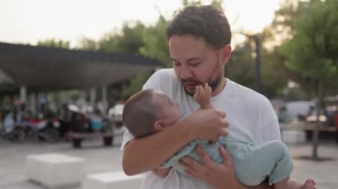 Happy father is holding cute baby and kisses while he is laughing. High quality 4k footage