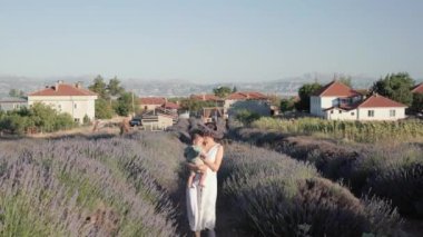 Beautiful woman with baby on lavender fields at sunset. Wreath of lavender. High quality 4k footage