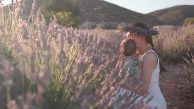 Beautiful woman with baby on lavender fields at sunset. Wreath of lavender. High quality 4k footage