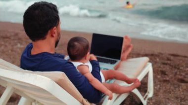 Freelancer man working on laptop and looking after the children. Remote work concept. work on vacation. 4 k High quality 4k footage