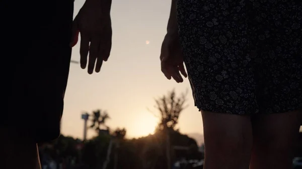 Close up view of silhouette of hands joining together with sunset on the background. High quality 4k footage