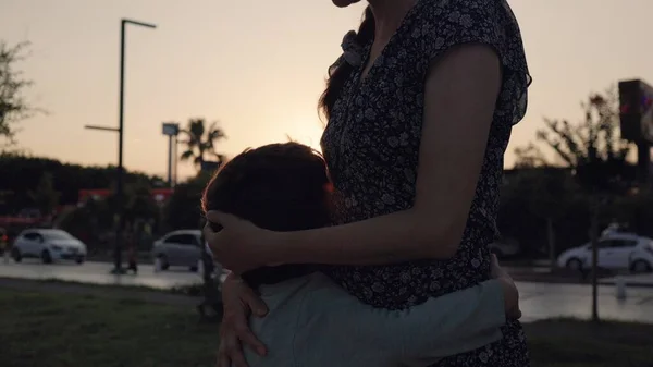 Silhouette of Happy kid is hugging mother on sunset background. High quality 4k footage