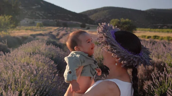 Beautiful woman with baby on lavender fields at sunset. Wreath of lavender. High quality 4k footage