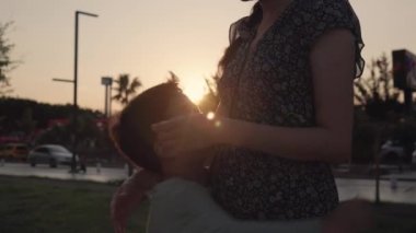 Silhouette of Happy kid is hugging mother on sunset background. High quality 4k footage