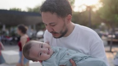 Happy father is holding cute baby and kisses while he is laughing. High quality 4k footage