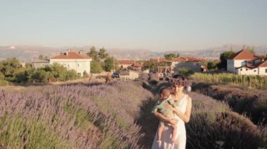 Beautiful woman with baby on lavender fields at sunset. Wreath of lavender. High quality 4k footage