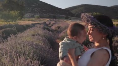 Beautiful woman with baby on lavender fields at sunset. Wreath of lavender. High quality 4k footage